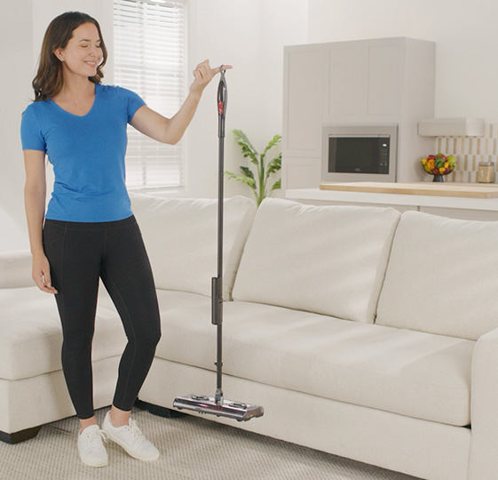 Woman holding up Swivel Sweeper Turbo S with one finger to show how light it is